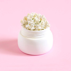 Creative idea: jar with flowers of white lilac as cosmetic cream