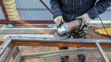 Worker cuts metal for doors at a construction site