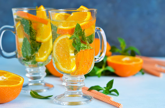 Cold summer drink. Lemonade with mint and orange on a blue background.