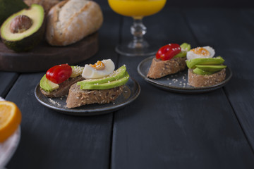 Toasts with avocado, yatsom and cherry tomatoes, on a black wooden background. Healthy and tasty food. Fitness food