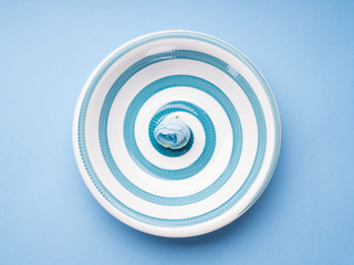 Blue pastel ceramic dish with hypnotizing spiral. Abstract food, tableware crockery concept