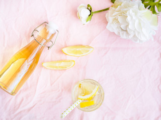 Hollunderblüten Saft, Zitrone und eine Flasche auf einer rosa Decke