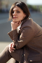 High fashion portrait of young elegant woman in brown suit walk on the street. enjoy summer lights. Fashion photo
