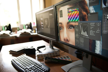 Desktop with two monitors, a keyboard, a camera, a diary, a palette for a designer, a retoucher, a photographer. With the image of the model on the monitors in special programs for retouching. - obrazy, fototapety, plakaty