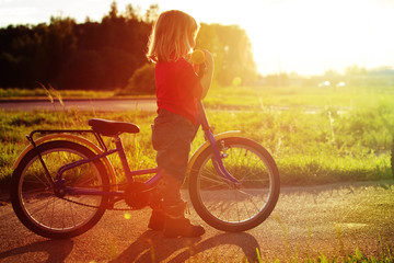 Obraz premium little girl riding bike at sunset