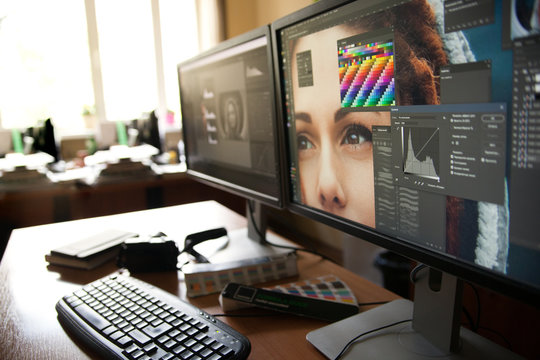 Desktop with two monitors, a keyboard, a camera, a diary, a palette for a designer, a retoucher, a photographer. With the image of the model on the monitors in special programs for retouching.