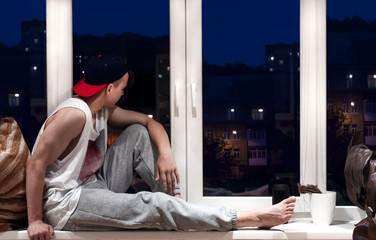 handsome young man sitting near window in the evening