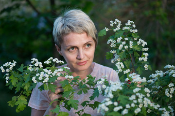 Portrait of a girl in a blooming garden. A woman is walking in the summer in the park. Happy middle-aged woman
