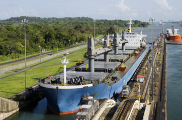 Two freighters, led by tugboats, are starting to transit the Panama Canal at the Gatun Locks on the Atlantic side.