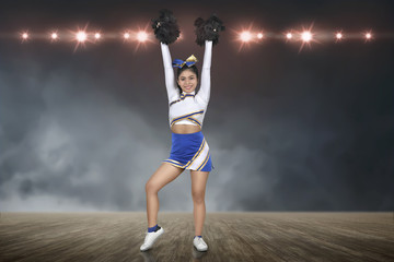 Smiling asian cheerleader perform with pom-poms