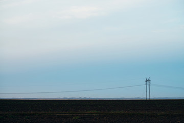 Power lines on background of blue sky close-up. Silhouette of electric pole with copy space. Wires...