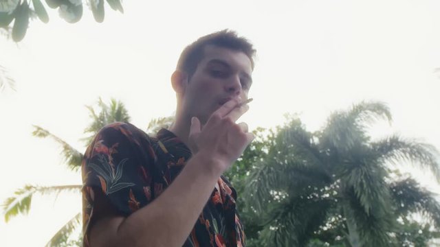 Young handsome guy in shirt smokes