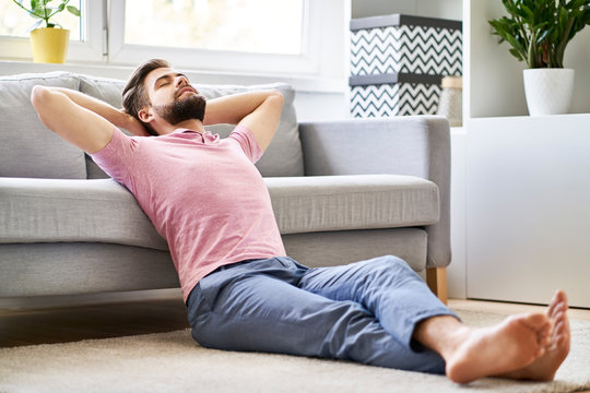 Daydreaming, relaxed man sitting on the floor at living room