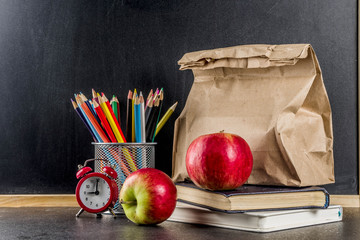 Healthy school food concept, lunch with apple, sandwich, books and alarm clock on chalkboard background copy space