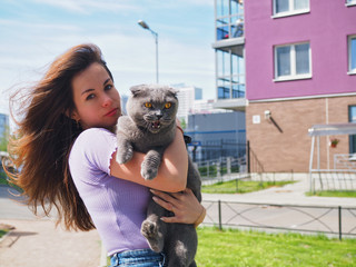 Girl walking with a cat, holding him in her arms