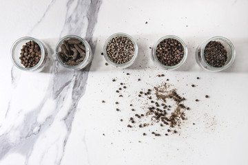 Variety of different black peppers allspice, pimento, long pepper, monks pepper, peppercorns and...