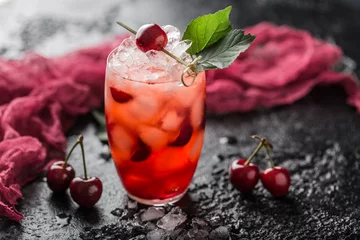 Foto op geborsteld aluminium Cocktail Fresh cherry cocktail. Fresh summer cocktail with cherry and ice cubes. Glass of cherry soda drink on dark stone background.