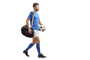 Soccer player with a bag and a football walking