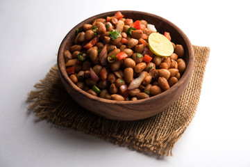 Boiled Peanut Chaat or Chatpata sing dana or shengdana or mungfali. served in a ceramic bowl over moody background