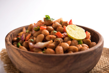 Boiled Peanut Chaat or Chatpata sing dana or shengdana or mungfali. served in a ceramic bowl over moody background