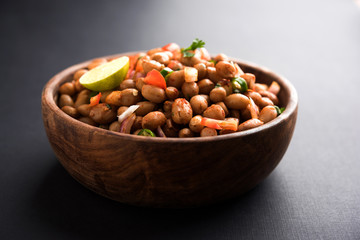 Naklejka na ściany i meble Boiled Peanut Chaat or Chatpata sing dana or shengdana or mungfali. served in a ceramic bowl over moody background