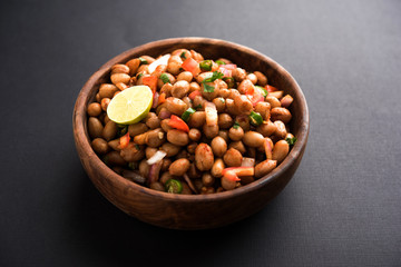 Boiled Peanut Chaat or Chatpata sing dana or shengdana or mungfali. served in a ceramic bowl over moody background