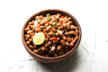 Boiled Peanut Chaat or Chatpata sing dana or shengdana or mungfali. served in a ceramic bowl over moody background