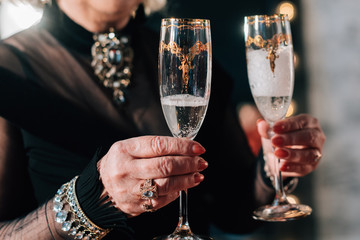 Calm pensioners standing with goblets full of sparkling alcohol drink and saying each other toasts.Happy senior couple enjoying glass of champagne