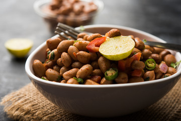 Boiled Peanut Chaat or Chatpata sing dana or shengdana or mungfali. served in a ceramic bowl over moody background