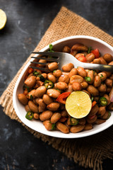 Boiled Peanut Chaat or Chatpata sing dana or shengdana or mungfali. served in a ceramic bowl over moody background