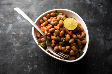 Boiled Peanut Chaat or Chatpata sing dana or shengdana or mungfali. served in a ceramic bowl over moody background