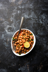 Boiled Peanut Chaat or Chatpata sing dana or shengdana or mungfali. served in a ceramic bowl over moody background