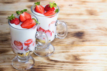 Tasty strawberry dessert with cream and fresh fruits in glasses on a rustic table