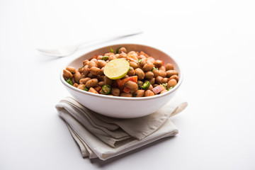 Boiled Peanut Chaat or Chatpata sing dana or shengdana or mungfali. served in a ceramic bowl over moody background