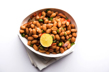 Boiled Peanut Chaat or Chatpata sing dana or shengdana or mungfali. served in a ceramic bowl over moody background