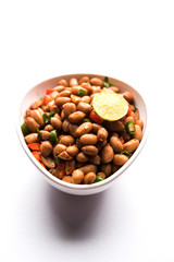 Boiled Peanut Chaat or Chatpata sing dana or shengdana or mungfali. served in a ceramic bowl over moody background