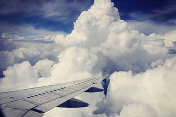 Fototapeta premium View from airplane, carrier wing and beautiful cumulus of white clouds against blue sky