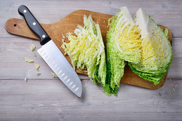 Savoy cabbage, cutting board and knife on wooden background. Top view