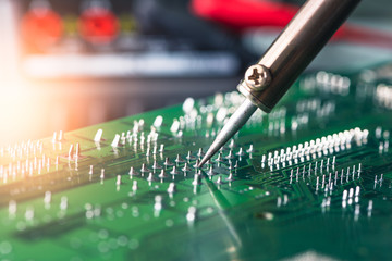 The asian technician repairing the computer's circuit board by soldering in the lab. the concept of...