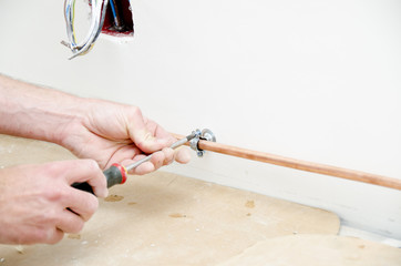 plombier fixant un tuyau en cuivre avec un tournevis