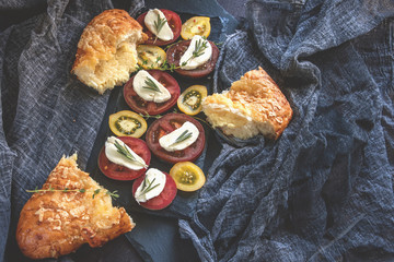 Italian Focaccia bread with cheese, rosemary, mozzarella cheese and tomatoes. Selective focus. Close-up.