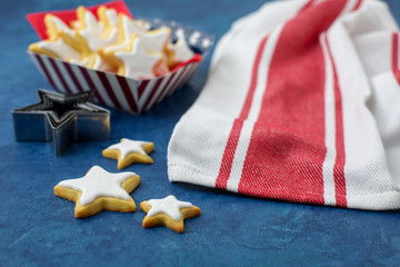 Obraz premium Homemade Star Shaped Sugar Cookies Served in Red, White, and Blue Paper Products against a Blue Background 