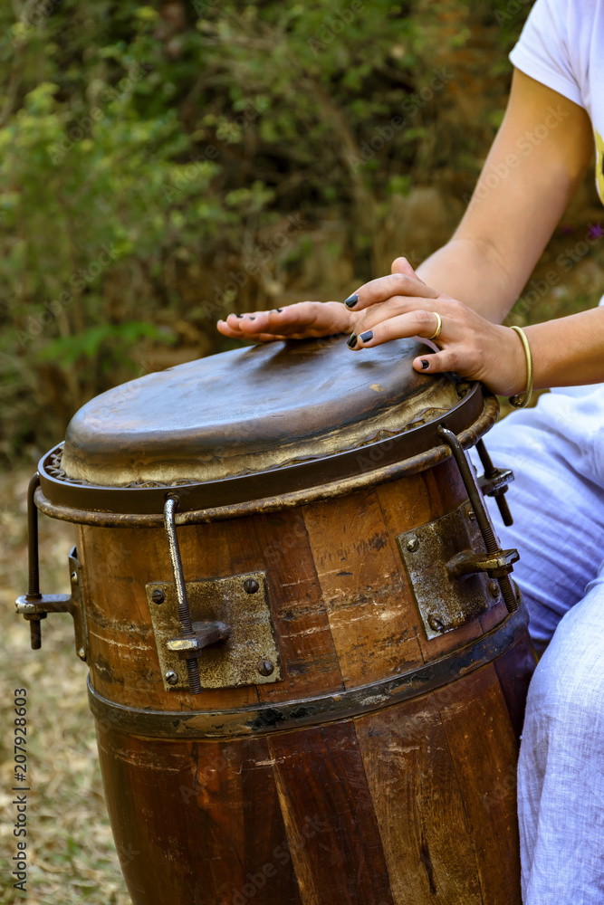 Wall mural Woman percussionist hands playing a drum called atabaque during brazilian folk music performance