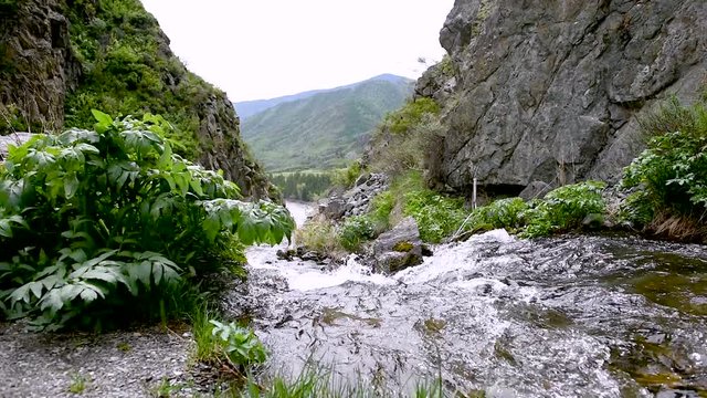 A mountain stream flows in the mountains into a deep valley.