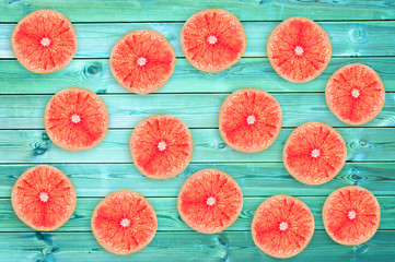 Many fresh grapefruit slices on blue wooden planks, summer background concept