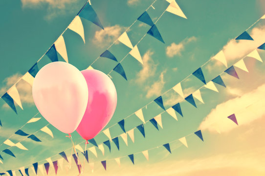 Pink air balloons on sky background with blue and white garlands, vintage summer party concept