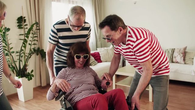 Two senior couples with wheelchair having fun at the party at home.