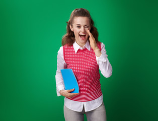 student woman with a blue notebook telling something and winking