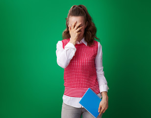 student woman with blue notebook facepalm isolated on green