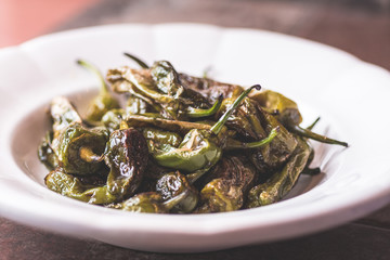 Green Padron Peppers with Olive Oil in Rustic White Plate. Pimientos de Padron.